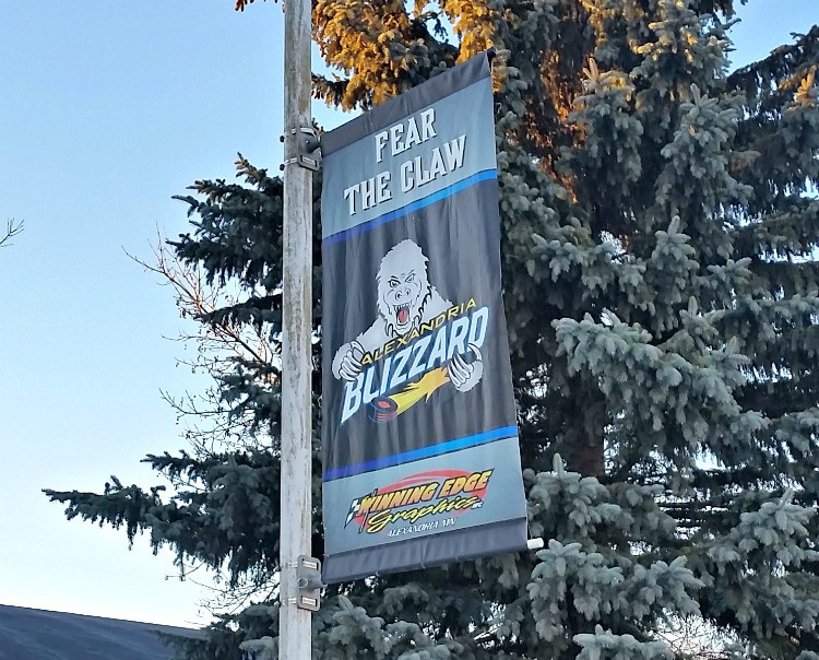 A street banner reads "FEAR THE CLAW" above a fierce Alexandria Blizzard white bear mascot and the words "ALEXANDRIA BLIZZARD," with evergreen trees in the background. The bottom features the logo "CUTTING EDGE SYNTHETICS.