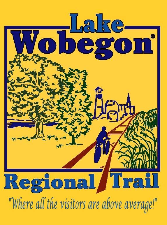 Logo for the Lake Wobegon Trail featuring a cyclist on a path, a large tree, town skyline, and the phrase “Where all the visitors are above average!” on a yellow background.
