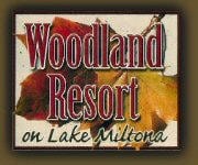 A sign with colorful autumn leaves in the background displays the text "Woodland Resort on Lake Miltona," capturing the inviting atmosphere of Woodland Resort.