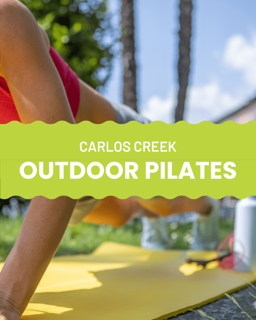 A person in workout clothes does a plank on a yellow mat outdoors during an Outdoor Pilates class. Green text reads "Carlos Creek Outdoor Pilates" across the center, with grass, trees, and blue sky in the background.