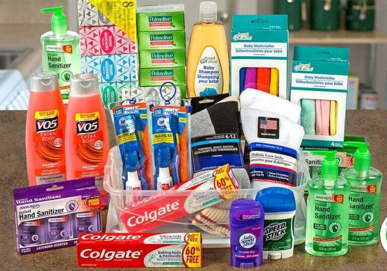 A variety of personal care and hygiene products—hand sanitizers, shampoo, toothpaste, toothbrushes, soap, tissues, socks, washcloths, and deodorant—are neatly arranged on a kitchen counter with a Dollar Tree logo in the corner.