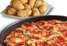 A delicious Dominos Pizza pan pizza topped with pepperoni and green peppers sits in the foreground, while a plate of golden-brown breaded chicken nuggets is in the background.