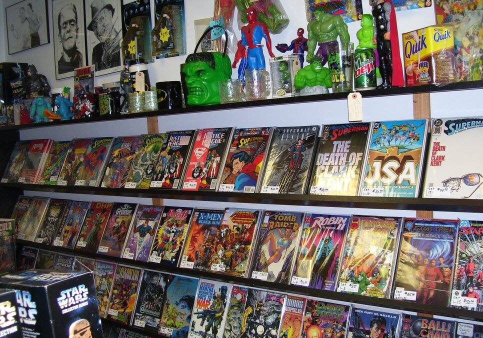 Shelves filled with comic books, superhero action figures, Hidden Treasures Collectibles, and posters. Items include Hulk, Spider-Man, and Superman figures, with colorful comic book covers prominently displayed.